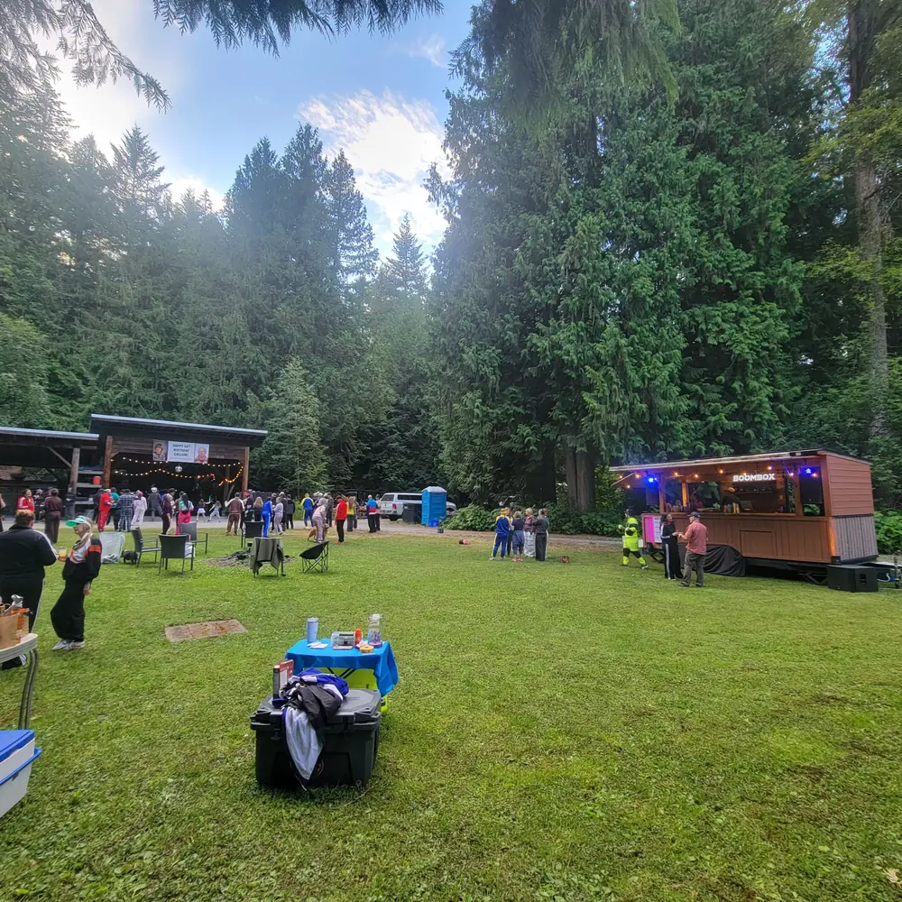 A crowd at an outdoor festival with the Boombox mobile bar on the field
